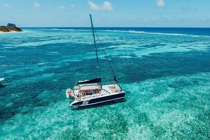 Catamaran sailing over clear turquoise waters near North Ilot Gabriel on a sunny day.